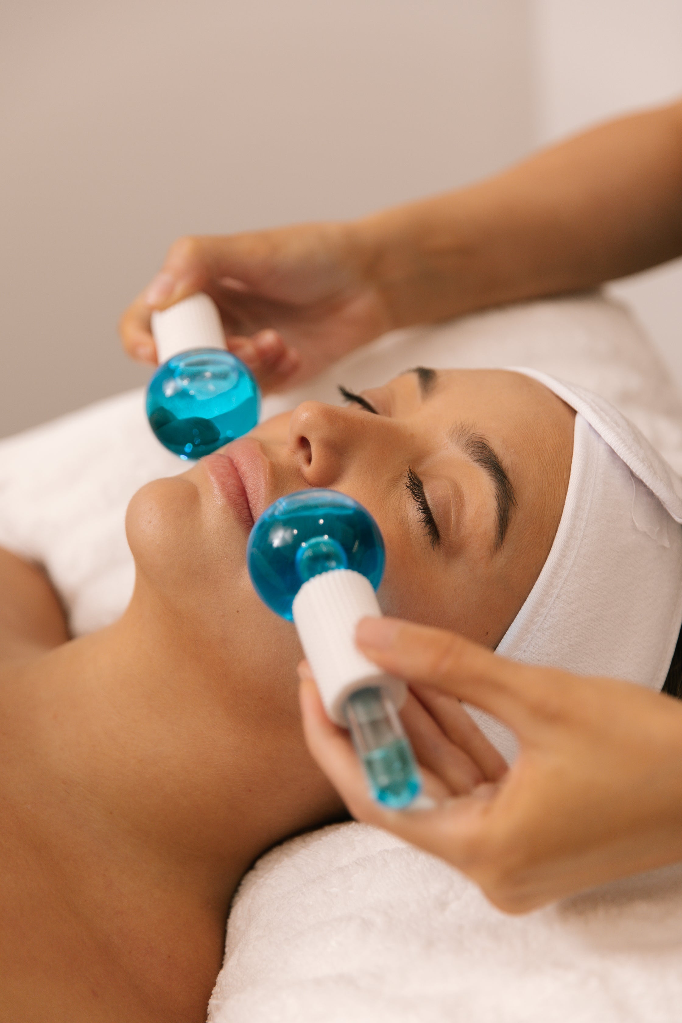 Cooling globes being glided over a client's face during a facial treatment at Plump Aesthetic Clinic